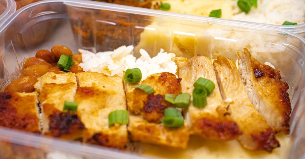 作り置きのために清潔なキッチンで保存容器に料理を丁寧に詰める様子