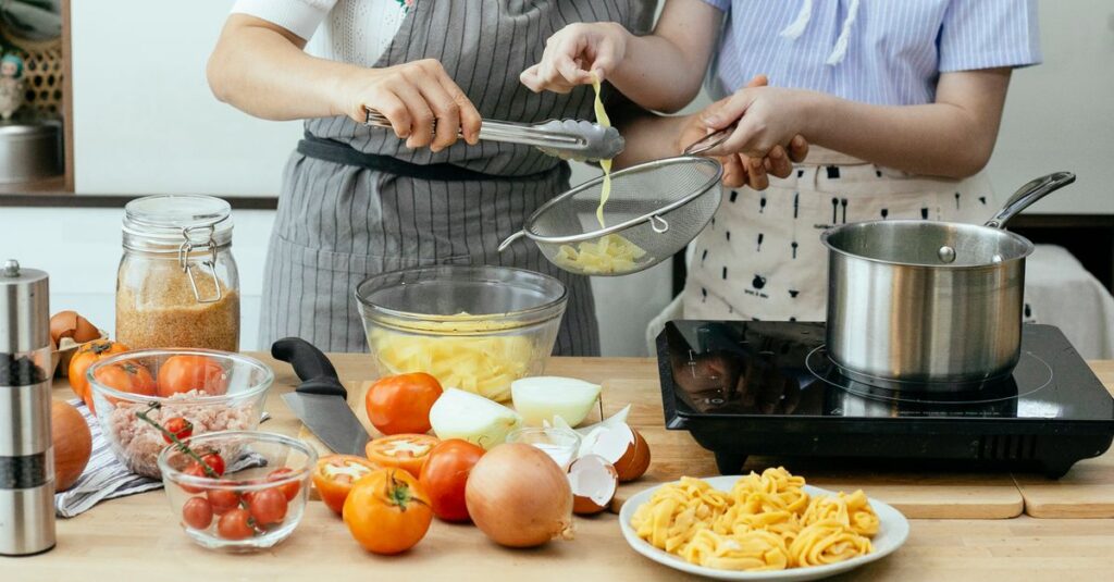 キッチンでミールキットの食材を調理する様子。色鮮やかな野菜や肉が並び、家族で料理を楽しむイメージ。
