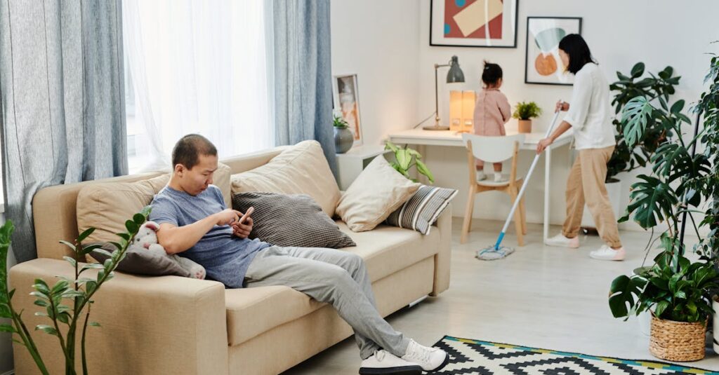 スマートフォンで家事分担アプリ（TimeTreeやOurHomeなど）を操作する夫婦の手元。